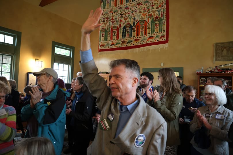 John Cloutier waving to a packed room of supporters at a campaign gathering